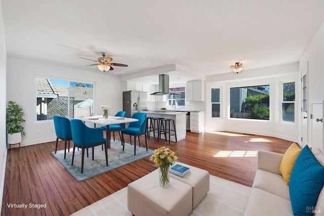 living room with light wood-type flooring, ceiling fan, and baseboards