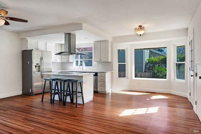 kitchen featuring a kitchen breakfast bar, stainless steel fridge with ice dispenser, dark wood-style floors, tasteful backsplash, and island exhaust hood