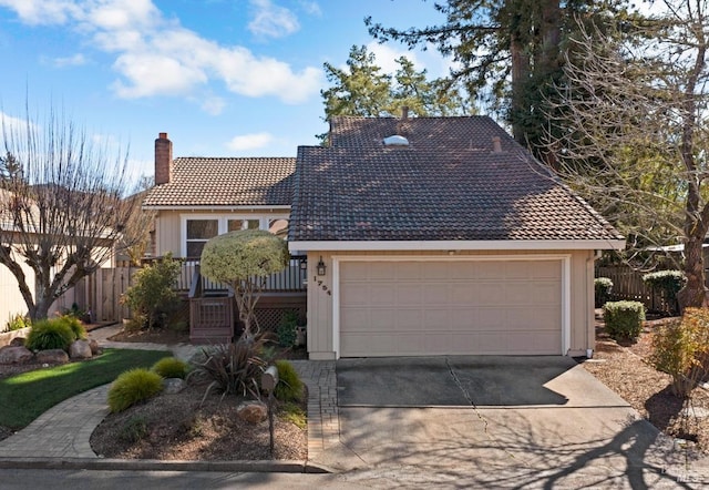 view of front of property with a garage, a tiled roof, a chimney, and fence