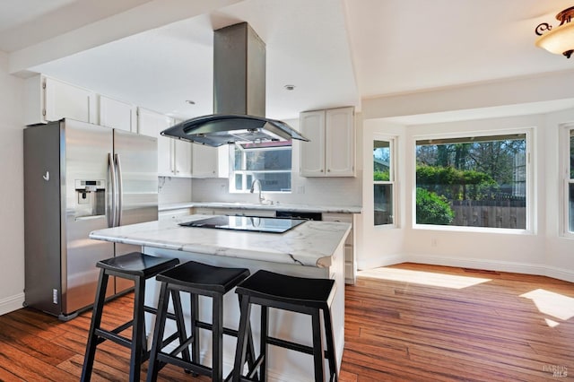 kitchen with white cabinets, island exhaust hood, backsplash, and stainless steel fridge with ice dispenser