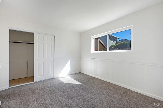 unfurnished bedroom with a closet, carpet flooring, and crown molding