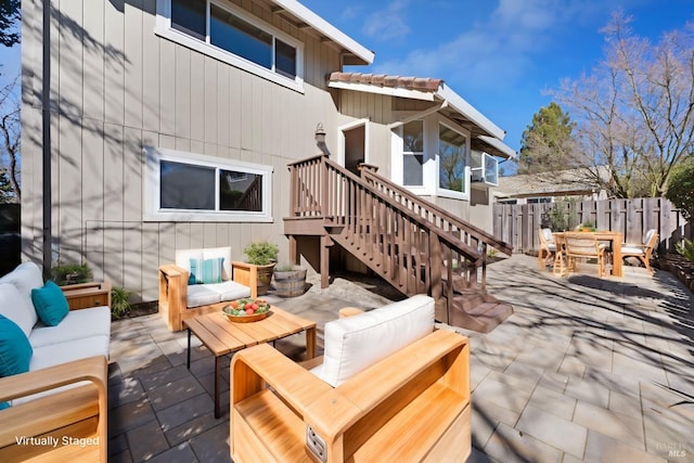 view of patio featuring outdoor dining space, stairway, fence, and an outdoor living space