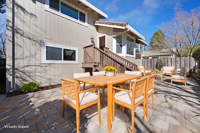 view of patio / terrace featuring outdoor dining area, fence, an outdoor hangout area, and stairs