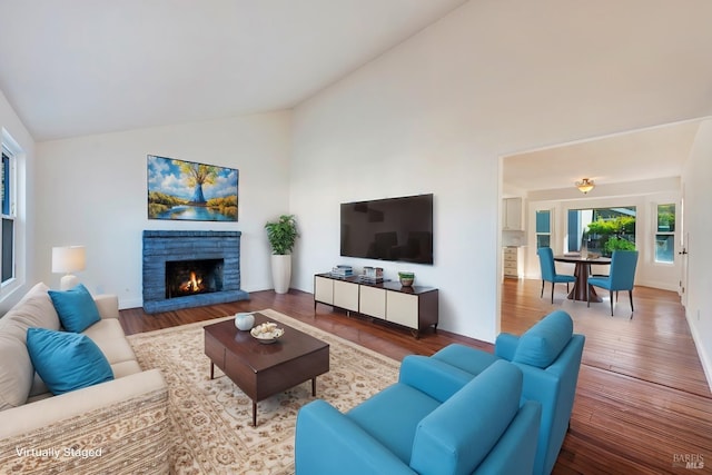 living room featuring high vaulted ceiling, a fireplace, baseboards, and wood finished floors