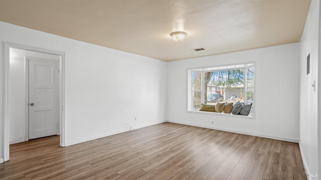 spare room with visible vents, baseboards, and wood finished floors