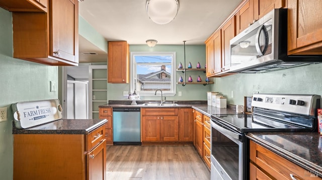 kitchen with visible vents, light wood-style flooring, a sink, appliances with stainless steel finishes, and brown cabinetry