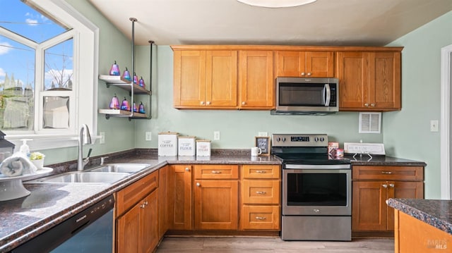 kitchen with a sink, brown cabinets, appliances with stainless steel finishes, and light wood finished floors