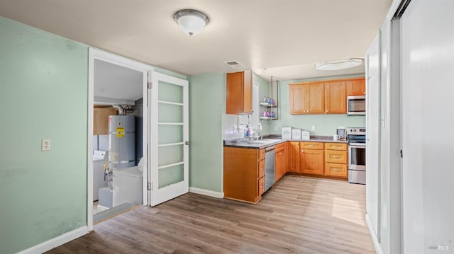 kitchen featuring stainless steel appliances, secured water heater, light wood-style flooring, and visible vents