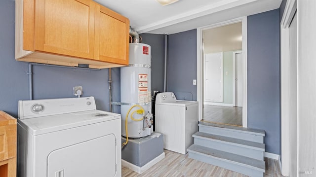 laundry room featuring secured water heater, cabinet space, independent washer and dryer, and light wood-type flooring