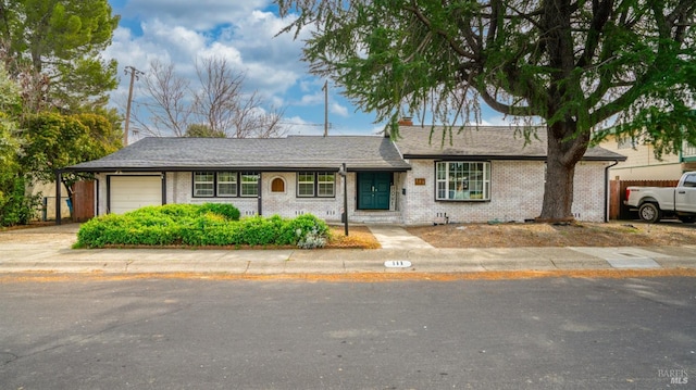 single story home featuring driveway, roof with shingles, a chimney, a garage, and brick siding