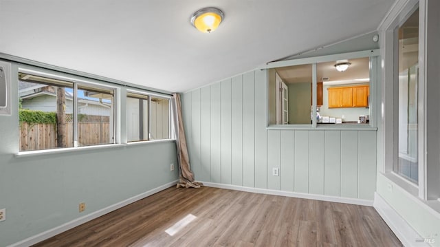 empty room with vaulted ceiling, wood finished floors, and baseboards