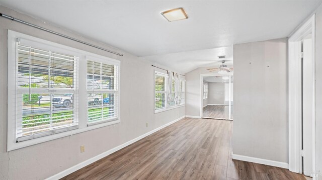 unfurnished room featuring ceiling fan, baseboards, wood finished floors, and vaulted ceiling