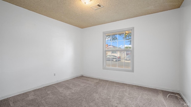 carpeted spare room with visible vents, a textured ceiling, and baseboards