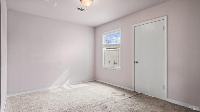 carpeted spare room with visible vents and baseboards