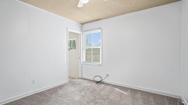 carpeted spare room featuring baseboards, a textured ceiling, and a ceiling fan