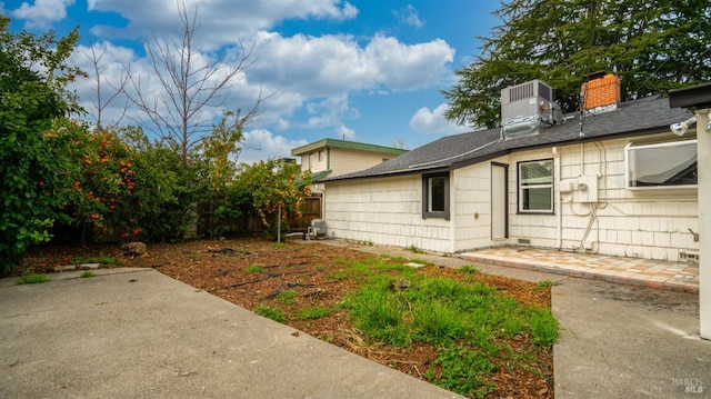 exterior space with a patio, fence, roof with shingles, crawl space, and central air condition unit