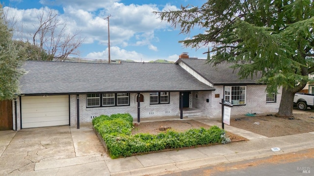 ranch-style house featuring a chimney, a shingled roof, concrete driveway, a garage, and brick siding