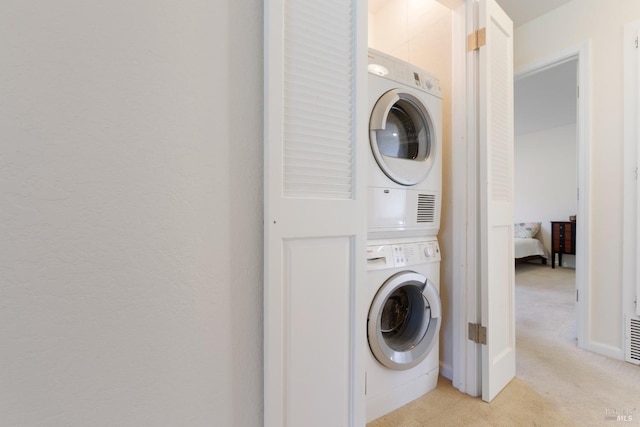 washroom with stacked washer / dryer, laundry area, light carpet, and visible vents