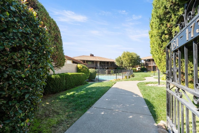 view of property's community featuring a lawn and fence