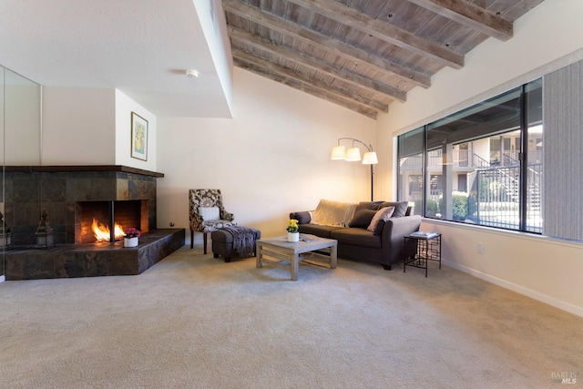 carpeted living area featuring lofted ceiling with beams, a tile fireplace, wood ceiling, and baseboards