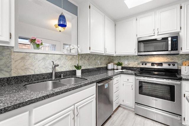 kitchen with white cabinets, decorative backsplash, stainless steel appliances, and a sink