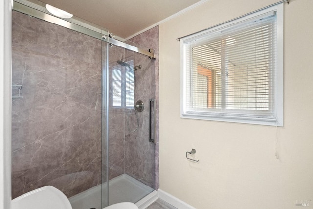 full bath with baseboards, crown molding, a shower stall, and toilet