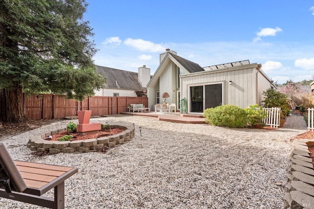 rear view of house with a patio area, a chimney, and fence