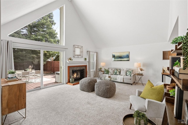 living room with a lit fireplace, high vaulted ceiling, and carpet flooring