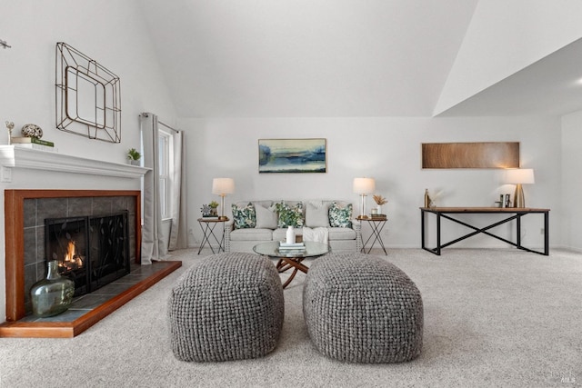 living room featuring a tile fireplace, baseboards, vaulted ceiling, and carpet