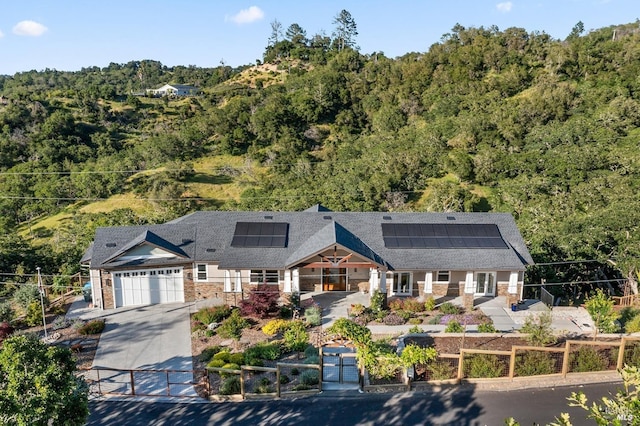 view of front of property with a garage, roof mounted solar panels, stone siding, and covered porch