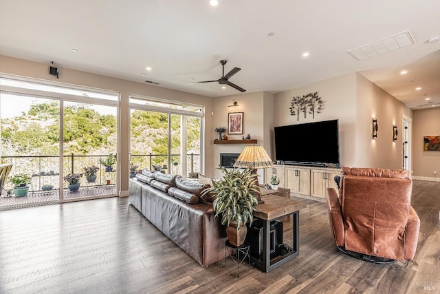 living room with recessed lighting, wood finished floors, visible vents, baseboards, and a glass covered fireplace