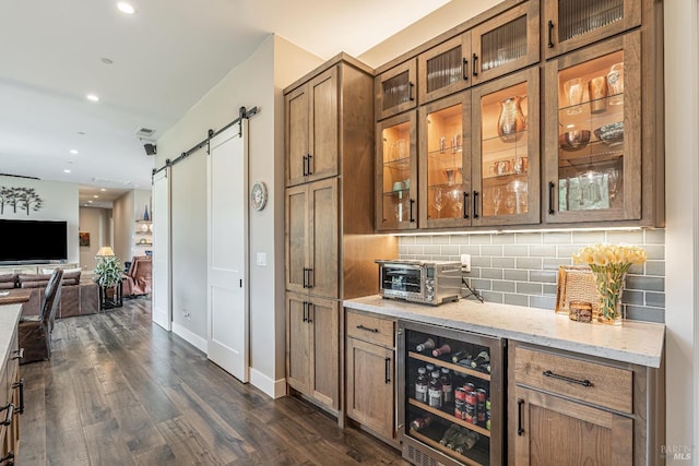 kitchen featuring dark wood-style floors, brown cabinetry, black appliances, a kitchen bar, and tasteful backsplash