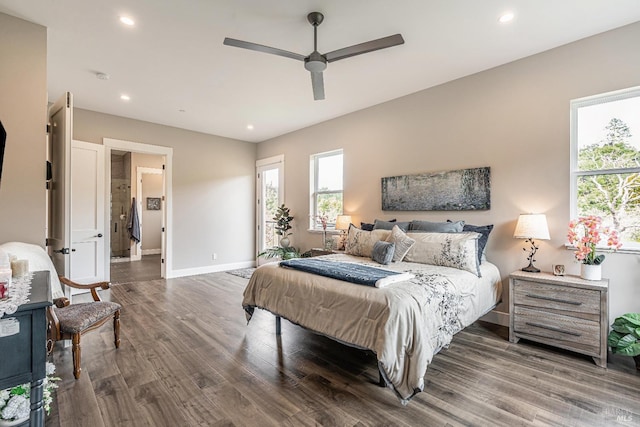 bedroom with a barn door, access to outside, wood finished floors, and multiple windows