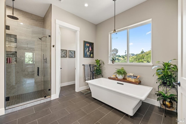 full bath featuring a freestanding bath, baseboards, tile patterned floors, and a stall shower