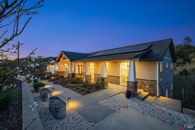 craftsman inspired home with stone siding and roof mounted solar panels