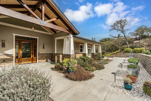 craftsman-style house featuring roof mounted solar panels, french doors, a porch, and stone siding