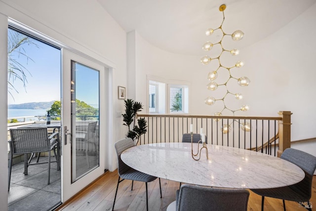 dining space with a wealth of natural light, light wood finished floors, and a notable chandelier