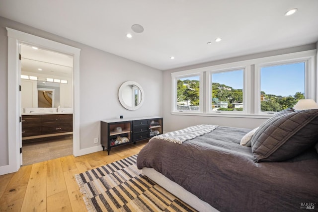 bedroom with baseboards, recessed lighting, ensuite bath, and light wood-style floors