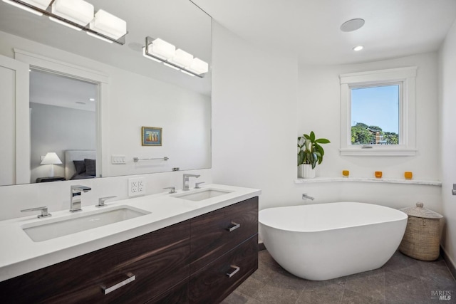 full bath with double vanity, a freestanding tub, a sink, and ensuite bathroom