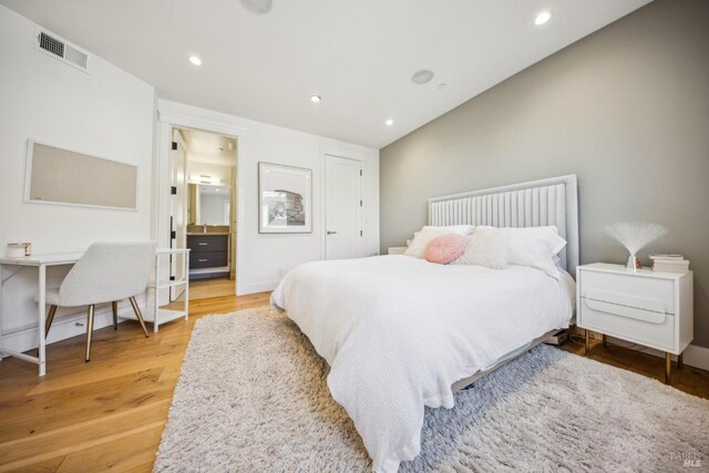 bedroom with light wood finished floors, baseboards, visible vents, ensuite bathroom, and recessed lighting