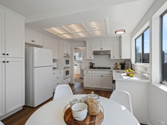 kitchen featuring white cabinets, a sink, dark wood-style flooring, and white appliances