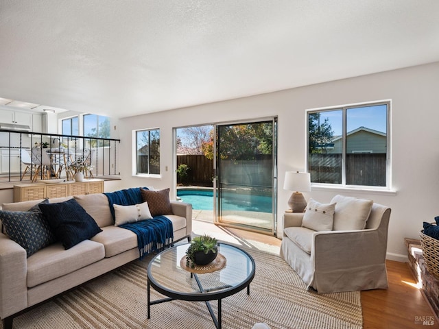 living area with a healthy amount of sunlight, a textured ceiling, baseboards, and wood finished floors