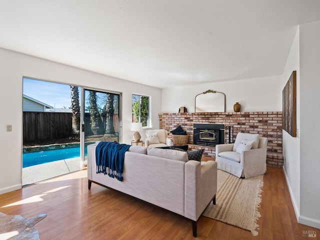 living area with baseboards, wood finished floors, and a brick fireplace