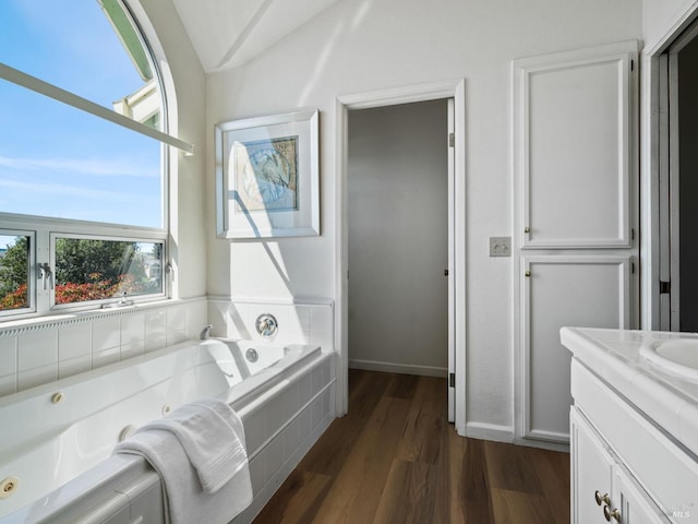 bathroom with a whirlpool tub, baseboards, wood finished floors, and vanity