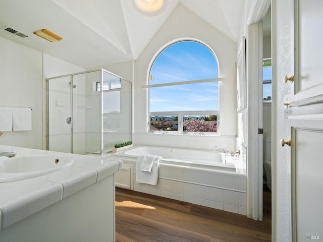 full bath with a stall shower, vaulted ceiling, vanity, wood finished floors, and a bath