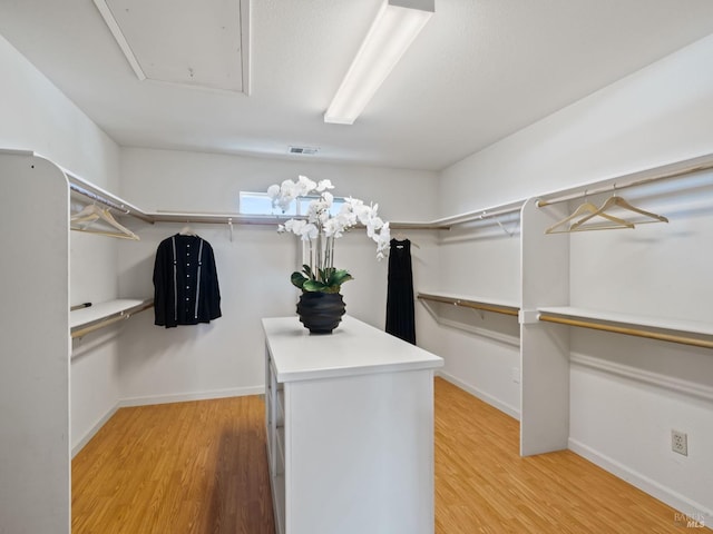 walk in closet featuring attic access, visible vents, and light wood-style flooring