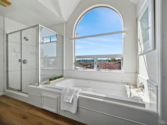 bathroom with a bath, a stall shower, vaulted ceiling, and wood finished floors