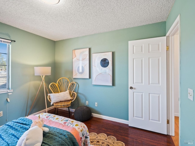 bedroom with a textured ceiling, baseboards, and wood finished floors