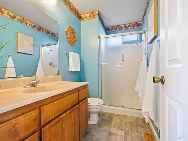 full bathroom featuring wood finished floors, a stall shower, toilet, and vanity