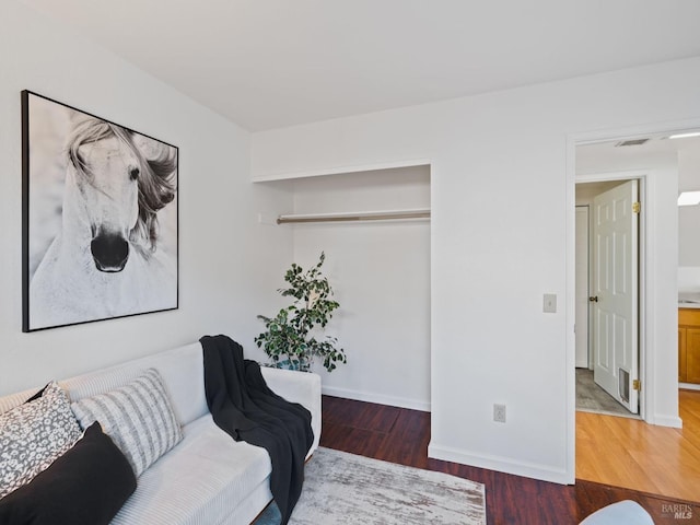 living room featuring visible vents, baseboards, and wood finished floors